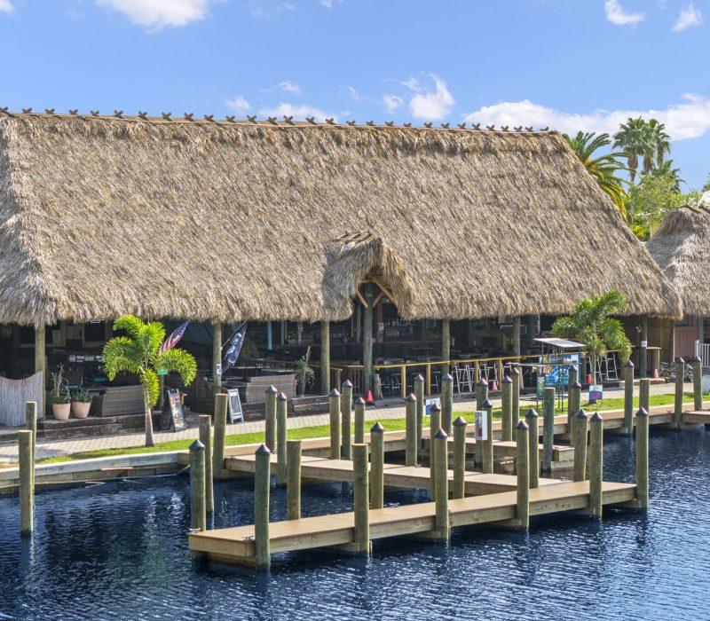 a building with a thatched roof and dock on water